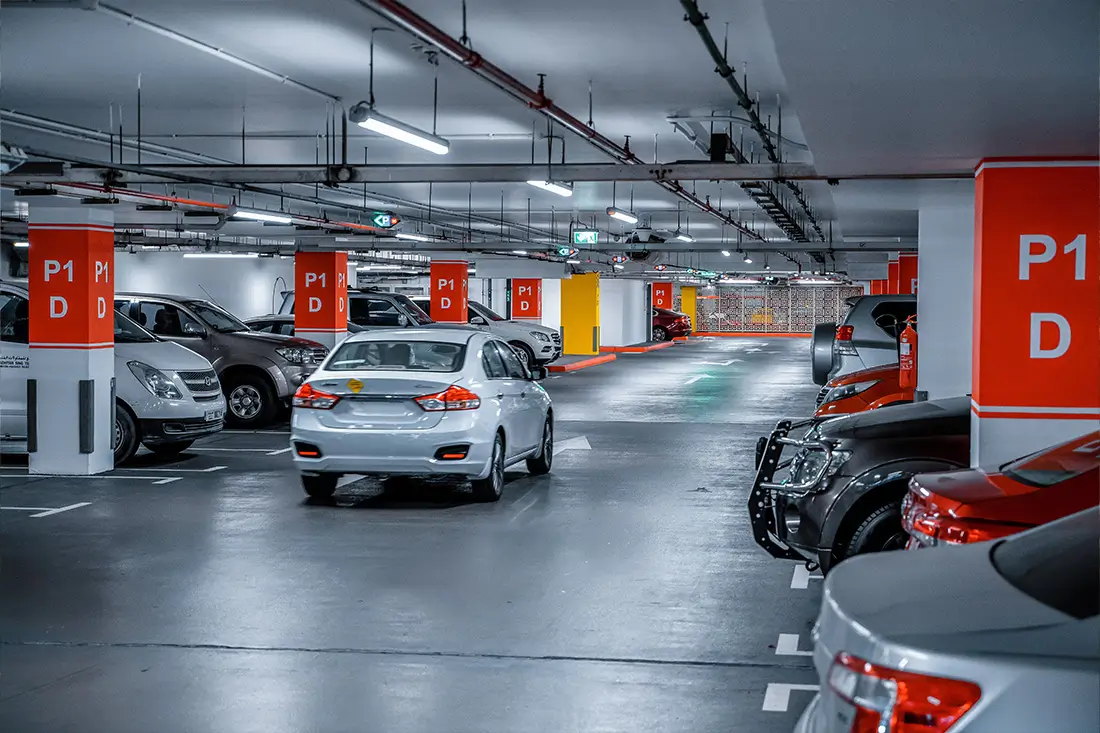 Parking podziemny – ujęcie wnętrza wielopoziomowego parkingu, podziemny parking z samochodami